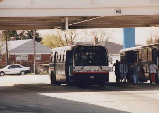 A white CTA bus with the number 4710 and destination sign reading '90 HARLEM' is stopped at a terminal with passengers boarding, while another bus and a white car are visible in the background.