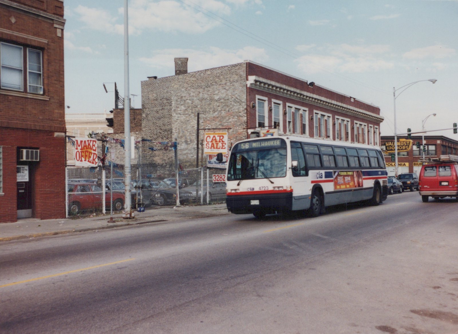 A white, blue, and red Chicago Transit Authority bus, number 4723, is driving down a city street with commercial buildings and signs in the background.