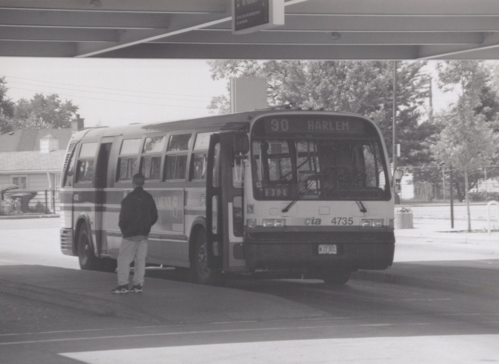 A black-and-white photo of a CTA bus numbered 4735 with destination 90 Harlem, stopped at a curb with one person boarding.