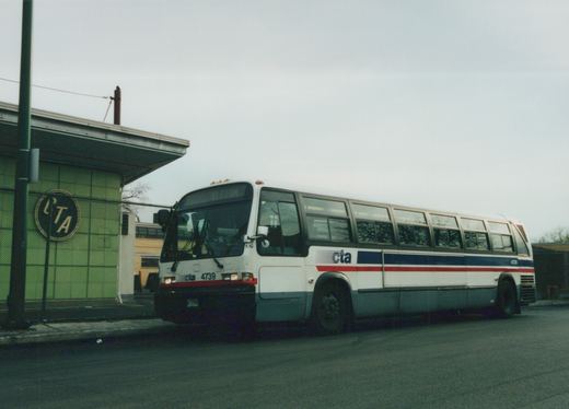 A white, blue, and red Chicago Transit Authority bus, numbered 4739, is parked on a street next to a green tiled building with a CTA sign.