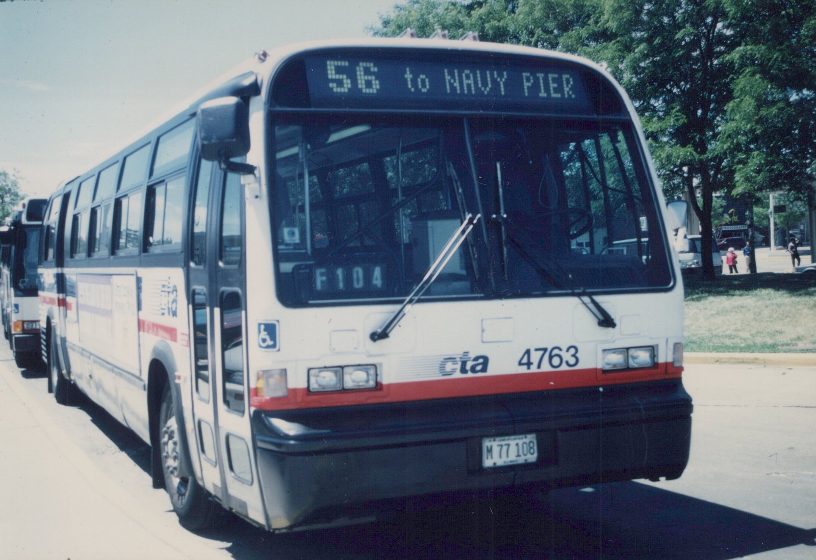 A white Chicago Transit Authority bus with red and blue stripes, number 4763, is shown from the front three-quarter view, displaying route 56 to Navy Pier on its sign.