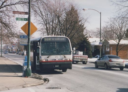 A white and red Chicago Transit Authority bus, number 4746, is stopped at a bus stop on a snowy street, with the destination '90N N Harlem' displayed; bare trees and a clear sky are in the background.