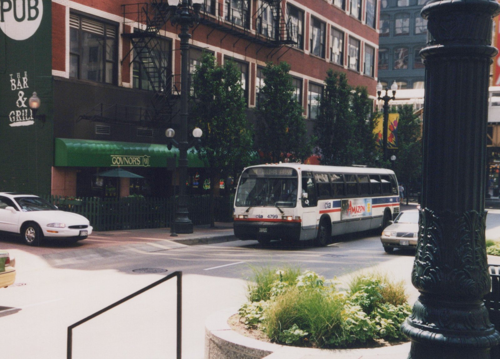 A white and blue CTA bus, number 4799, turns a corner on a city street next to a building with a green awning reading 'Govnor's Pub'.