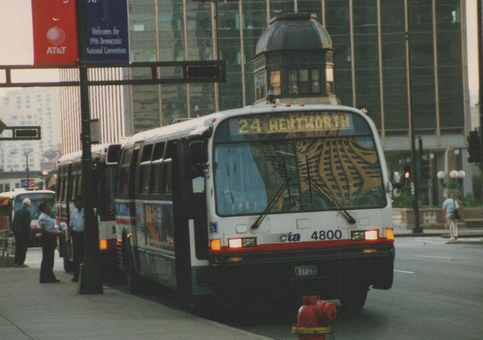 A white CTA bus with the route sign '24 WENTWORTH' is stopped on a city street, with a banner for the 1996 Democratic National Convention visible in the background.