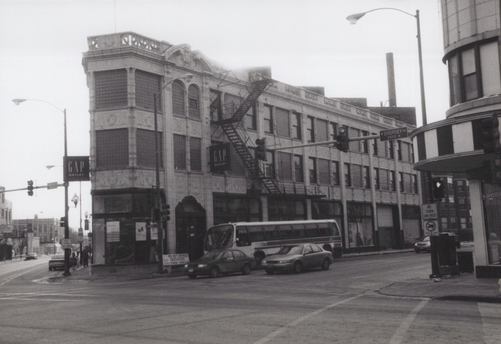 A black and white photo of a Chicago Transit Authority bus stopped at an intersection with a GAP Outlet store and street signs for Diversey Avenue visible.
