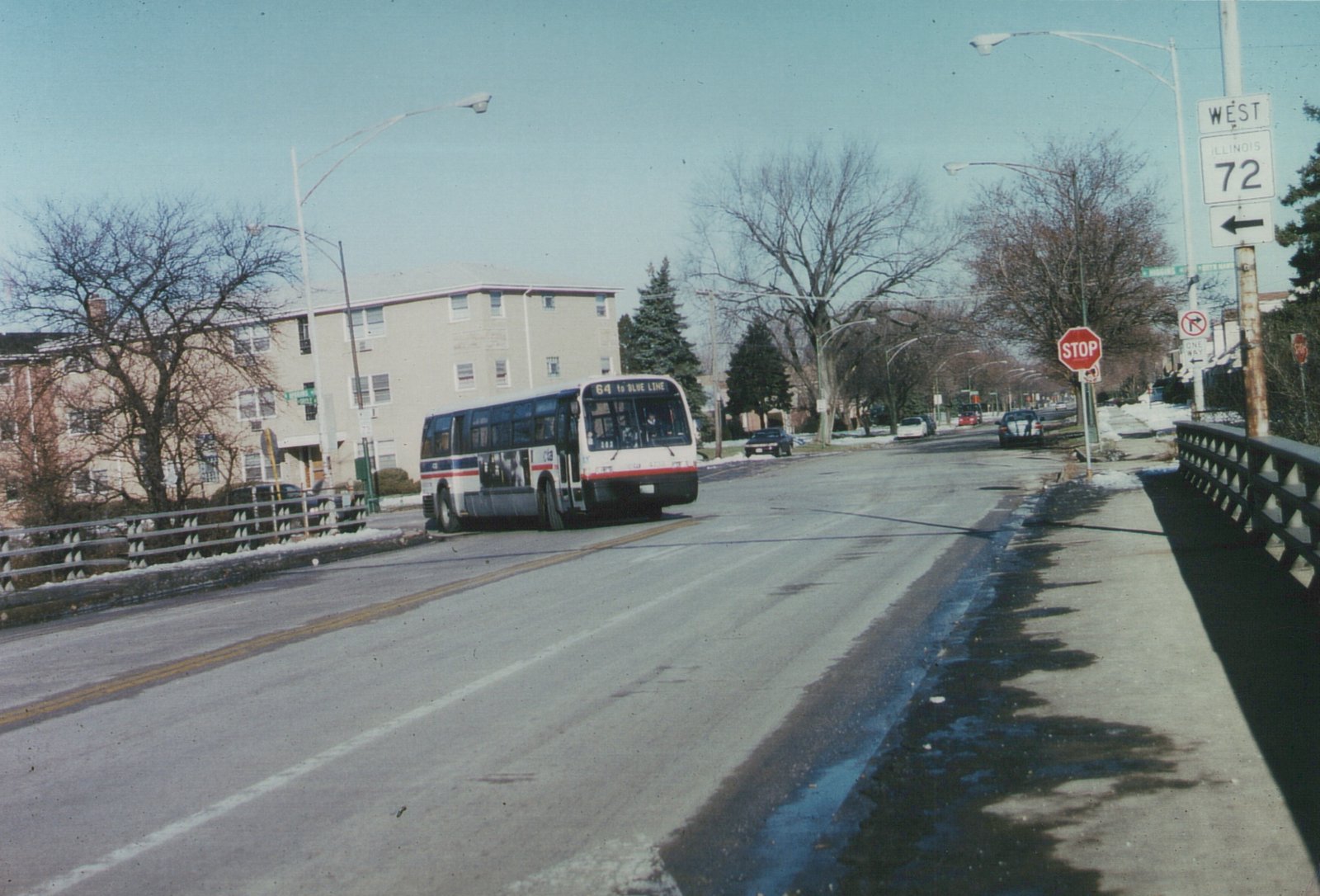A white, red, and blue Chicago Transit Authority bus, number 4736, is driving across a bridge on a sunny winter day, with bare trees and snow on the ground.