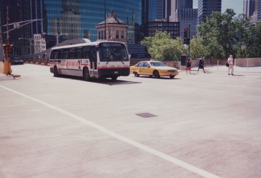 A white and red Chicago Transit Authority bus, number 4737 on route 41, is driving on a city street with modern skyscrapers in the background. A yellow taxi and several pedestrians are also visible.