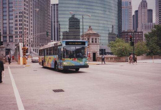 A colorfully painted Chicago Transit Authority bus, number 4041, drives on a city street with skyscrapers and a bridge in the background.