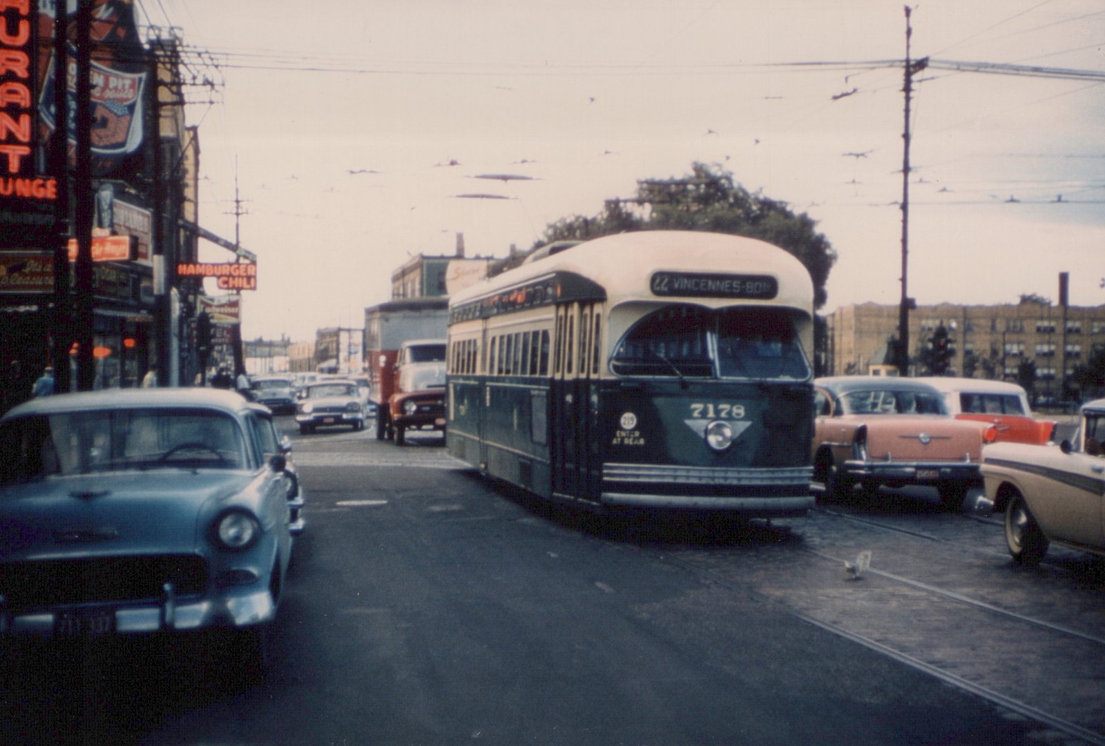 A green and cream PCC streetcar numbered 7178 on a Chicago street in 1953, surrounded by 1950s automobiles and storefronts.