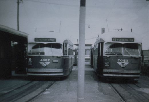 Front view of two Chicago Transit Authority PCC streetcars, numbers 4057 and 7040, parked side by side on streetcar tracks with destination signs visible, under overcast skies.