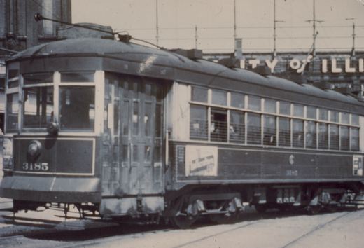 A vintage black-and-white photo of a Chicago Surface Lines streetcar numbered 3185, viewed from the front-left on a street with overhead wires and a building in the background.