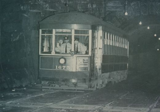 A vintage streetcar, number 1675, is shown inside a dimly lit tunnel, with two operators visible in the front cab and the destination sign reading 'DIVISION-CALIFORNIA'.
