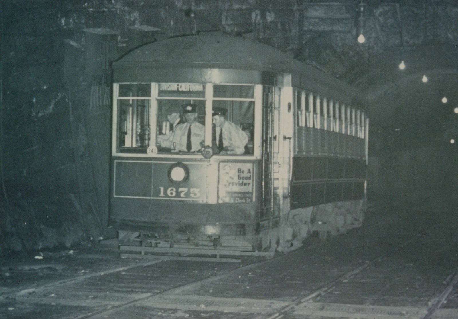 A vintage streetcar, number 1675, is shown inside a dimly lit tunnel, with two operators visible in the front cab and the destination sign reading 'DIVISION-CALIFORNIA'.