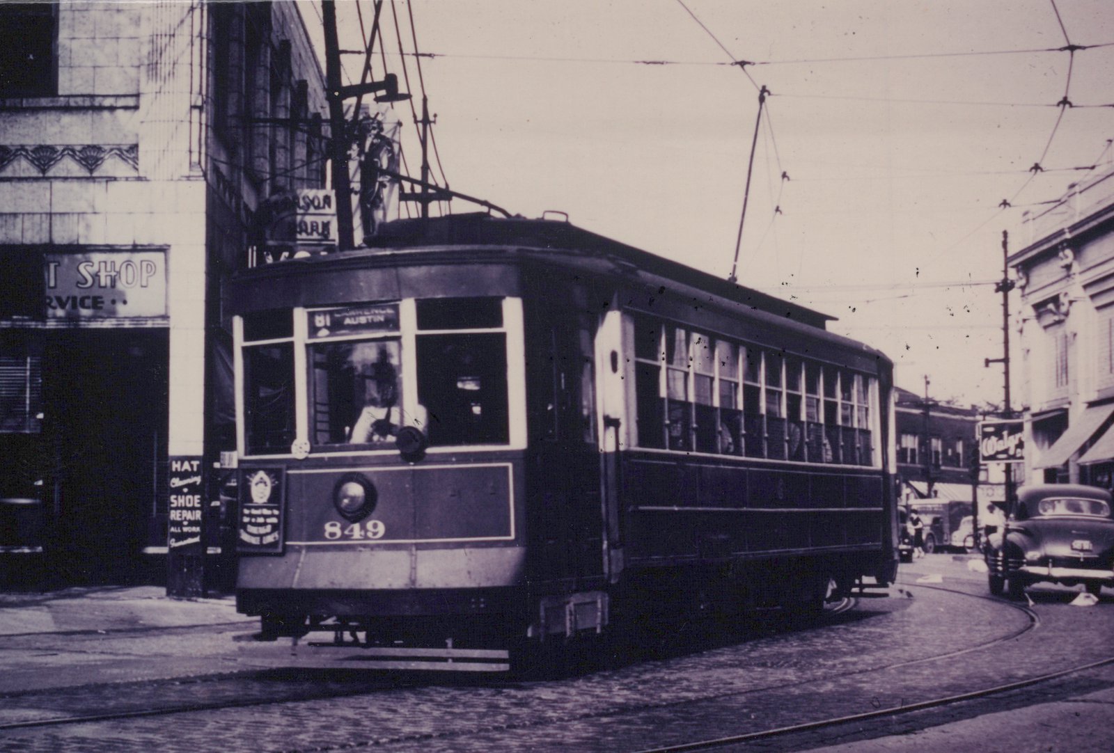 A vintage black and white photo of a streetcar with number 849 turning a corner on a city street, with a Walgreens sign visible in the background.