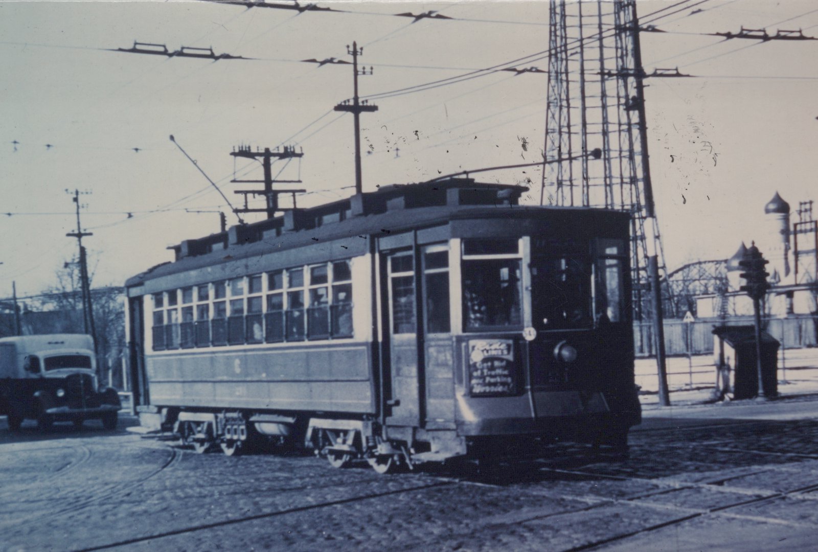 A vintage black and white photograph shows a CSL streetcar, number 211, on a cobblestone street with overhead wires, next to a pre-war delivery truck.