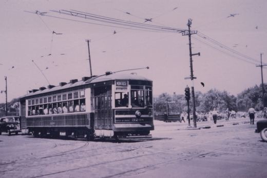 A vintage streetcar with the number 3298 and destination Montrose is shown on a city street with overhead wires, passengers visible inside, and a few pedestrians nearby.