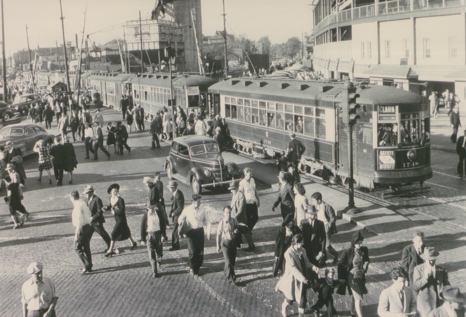 A black and white photo of a crowded street in Chicago where a Chicago Surface Lines streetcar, number 1748, is stopped at an intersection while pedestrians cross the tracks.