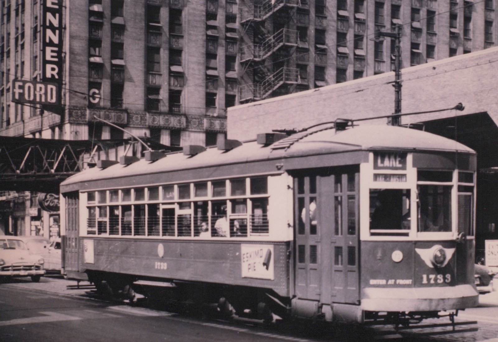 A vintage Chicago streetcar numbered 1783, running on the Lake route, is shown in a city street with a Ford dealership sign in the background and passengers visible inside.