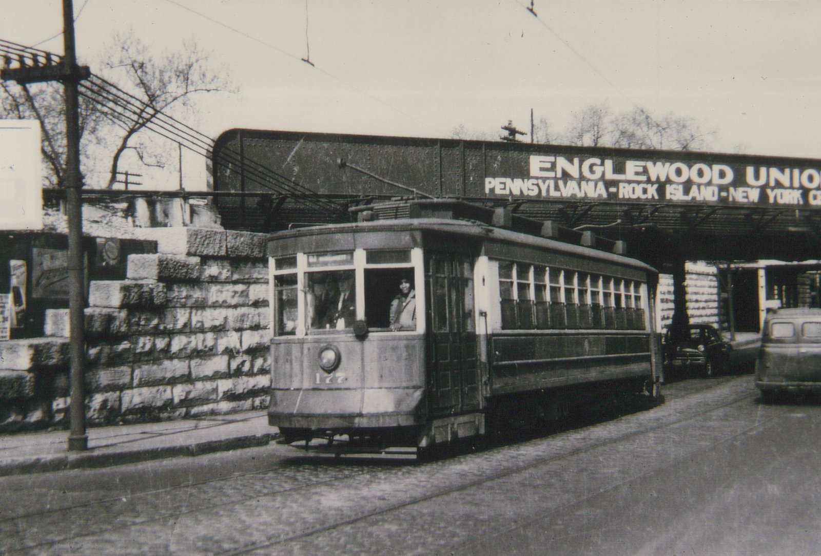 A vintage black-and-white photo of a streetcar numbered 127 running on a city street under a railway bridge marked 'Englewood Union'.