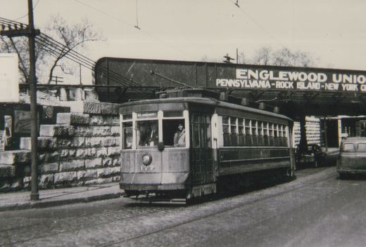 A vintage black-and-white photo of a streetcar numbered 127 running on a city street under a railway bridge marked 'Englewood Union'.