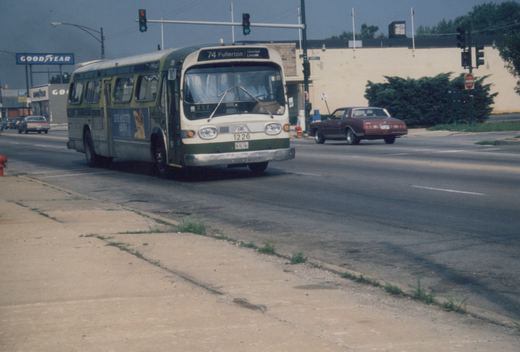 A green and cream CTA bus numbered 1226 is turning at a street intersection with traffic lights and other cars visible, under a clear sky.