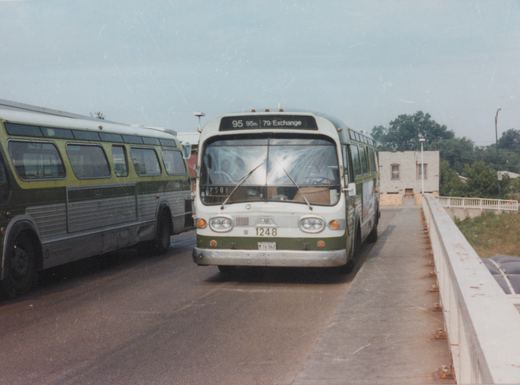 A white and green CTA bus with number 1248 on the front, driving across a bridge with another bus alongside.
