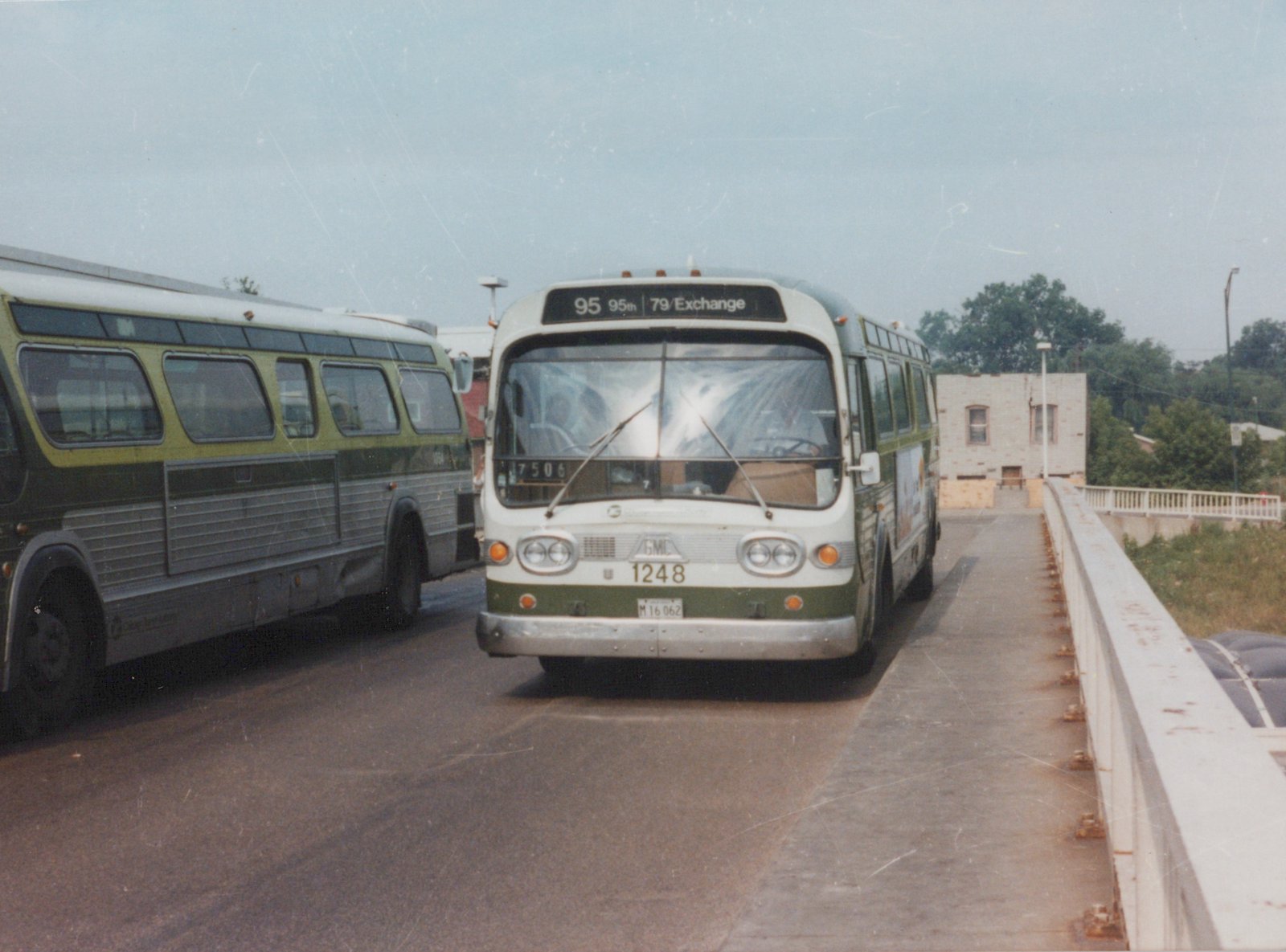 A white and green CTA bus with number 1248 on the front, driving across a bridge with another bus alongside.