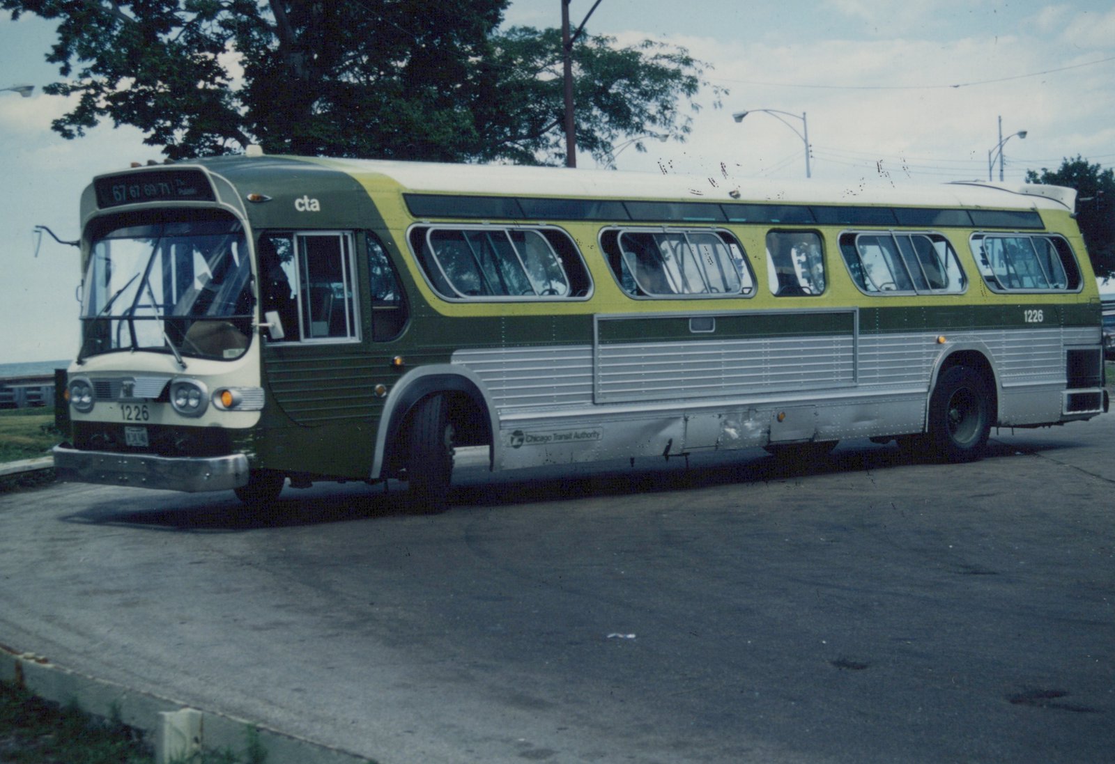 A green, yellow, and silver Chicago Transit Authority bus, number 1226, parked on a street with trees and a lake visible behind it.