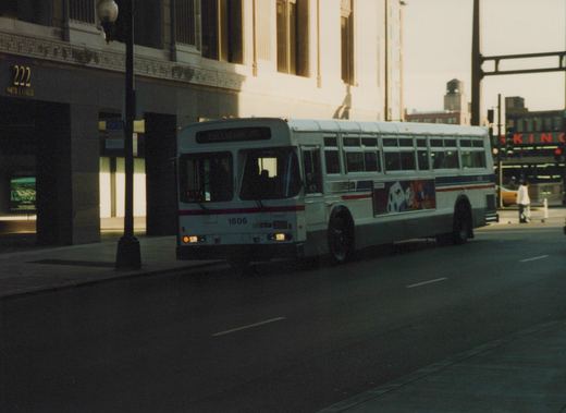 A white CTA bus with the number 1606 is parked on a city street next to a building marked 222 North La Salle.