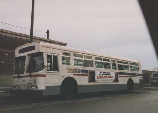 Side view of a white Chicago Transit Authority bus numbered 1621, showing an AIDS awareness ad on its side, parked on a wet street under an overcast sky.