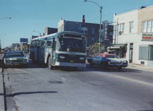 A green and white CTA bus, number 3724, on route 76 Diversy, is parked on a city street next to a red and blue taxi and a green car, with storefronts in the background.