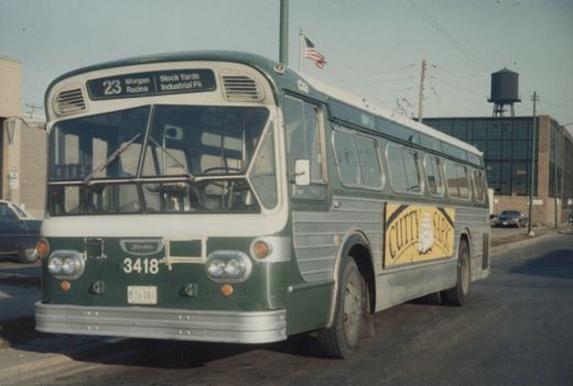A green and white CTA motor bus, number 3418, on route 23, with a Cutty Sark ad on its side, parked on a city street.