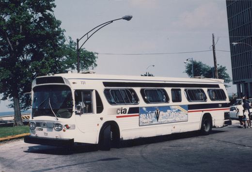 A white CTA motor bus numbered 731, displaying an advertisement for Grand Victoria Casino, is parked on a street with people walking nearby.