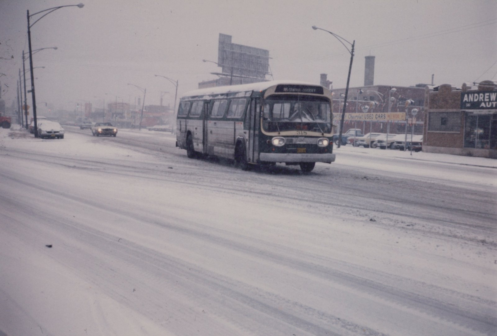 A green and white bus with the number 315 and route 95 Central-Diversey sign drives down a snow-covered street with cars and storefronts in the background.