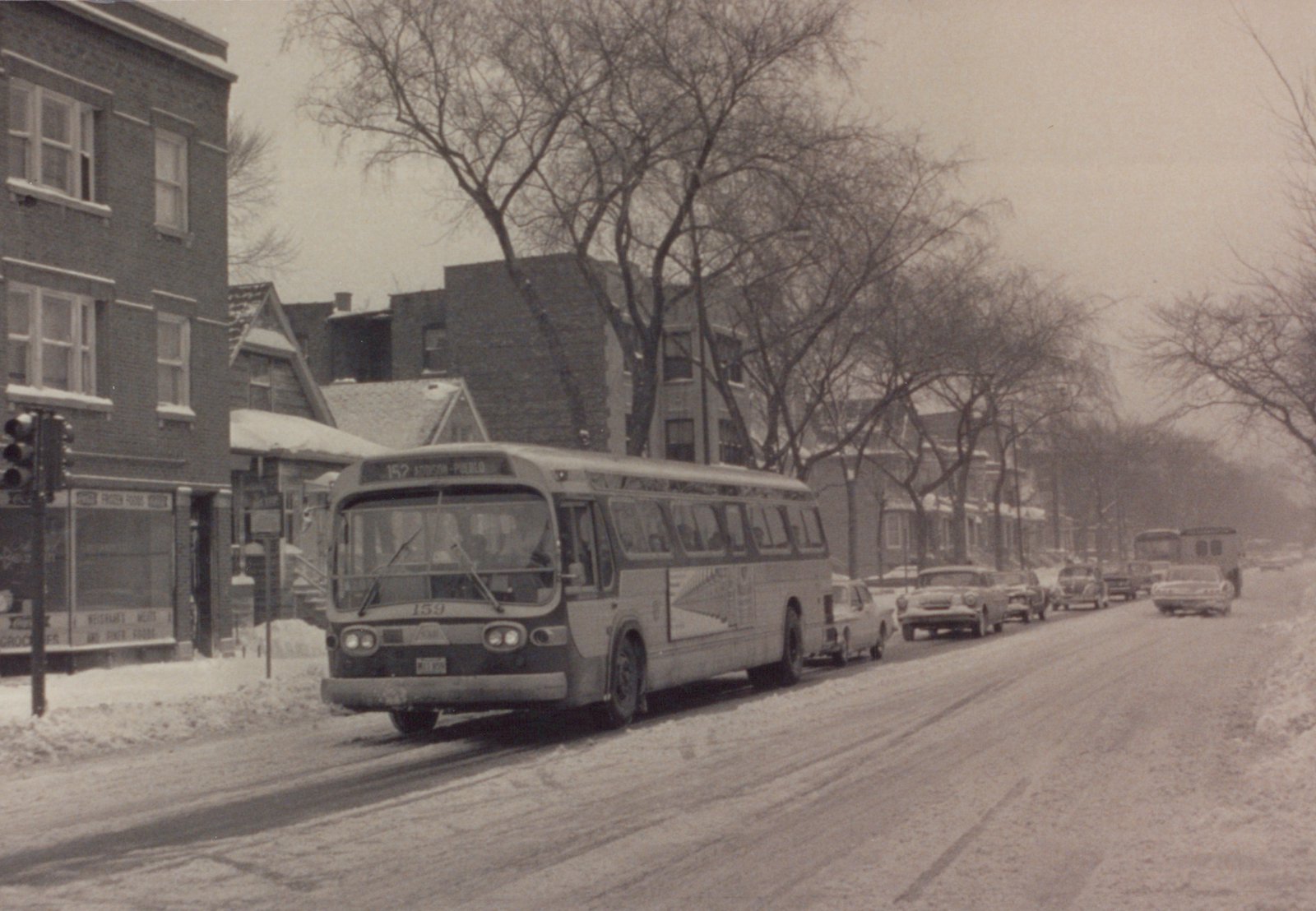 A vintage Chicago Transit Authority bus on a snow-covered street, with bare trees and parked cars lining the road.