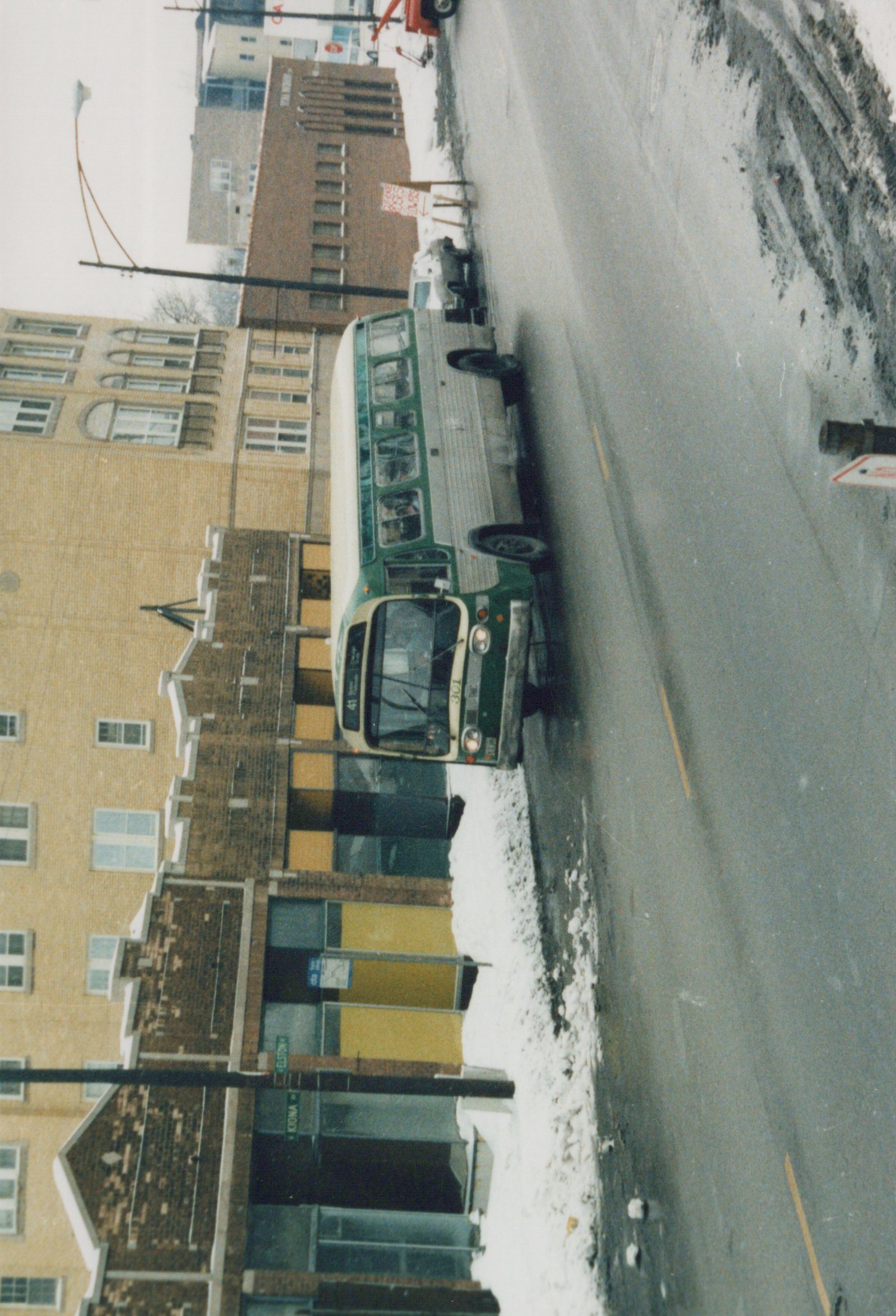 A green and cream Chicago Transit Authority bus, number 301, is parked on a snowy street corner at Elston and Kiona Streets.