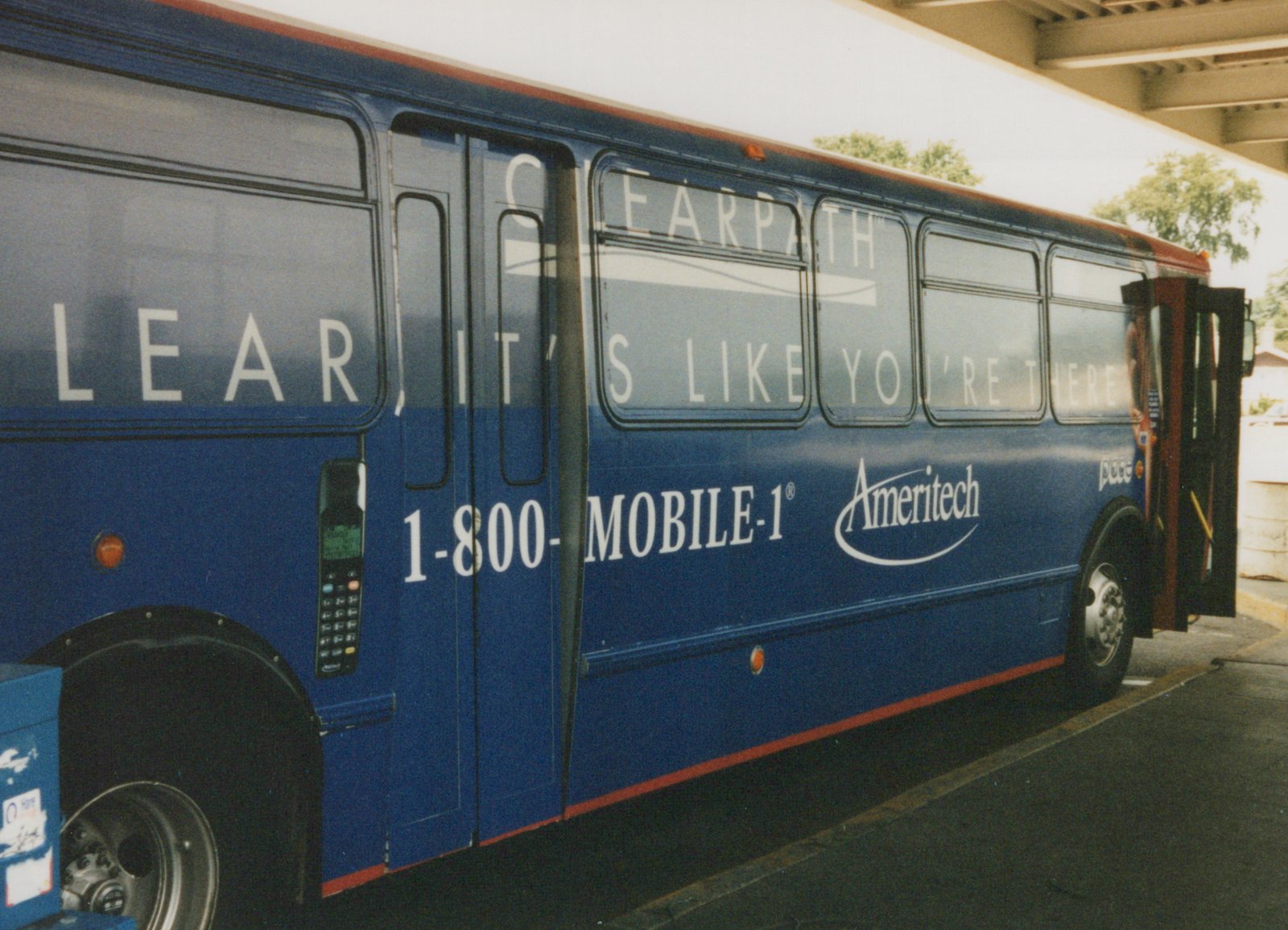 Side view of a blue Pace motor bus with 'Ameritech' and 'CLEARPATH' advertisements on its side, parked under a concrete overpass.