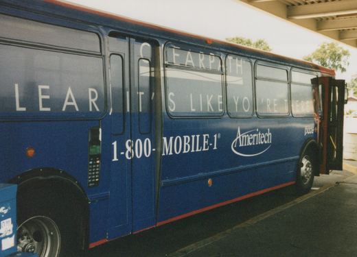 Side view of a blue Pace motor bus with 'Ameritech' and 'CLEARPATH' advertisements on its side, parked under a concrete overpass.