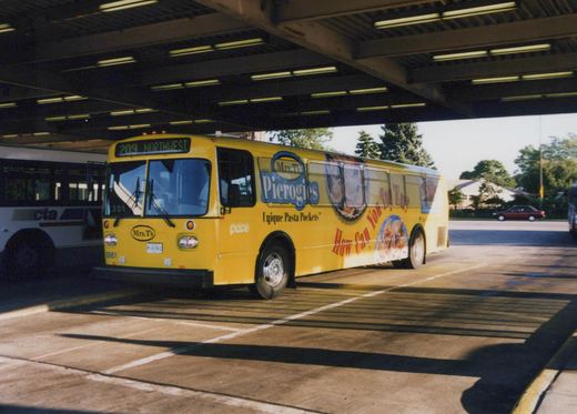 A yellow Pace bus, number 8861, with Mrs. T's Pierogies advertising on its side, is parked under a covered terminal roof, with a white CTA bus partially visible behind it.