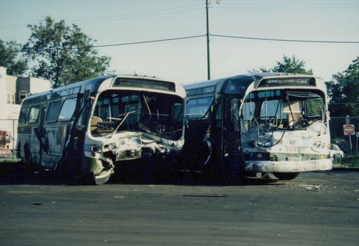 Two damaged CTA buses in a lot, one with a crushed front end and the other with a visible fleet number 9648 and destination sign reading '5 King Drive'.