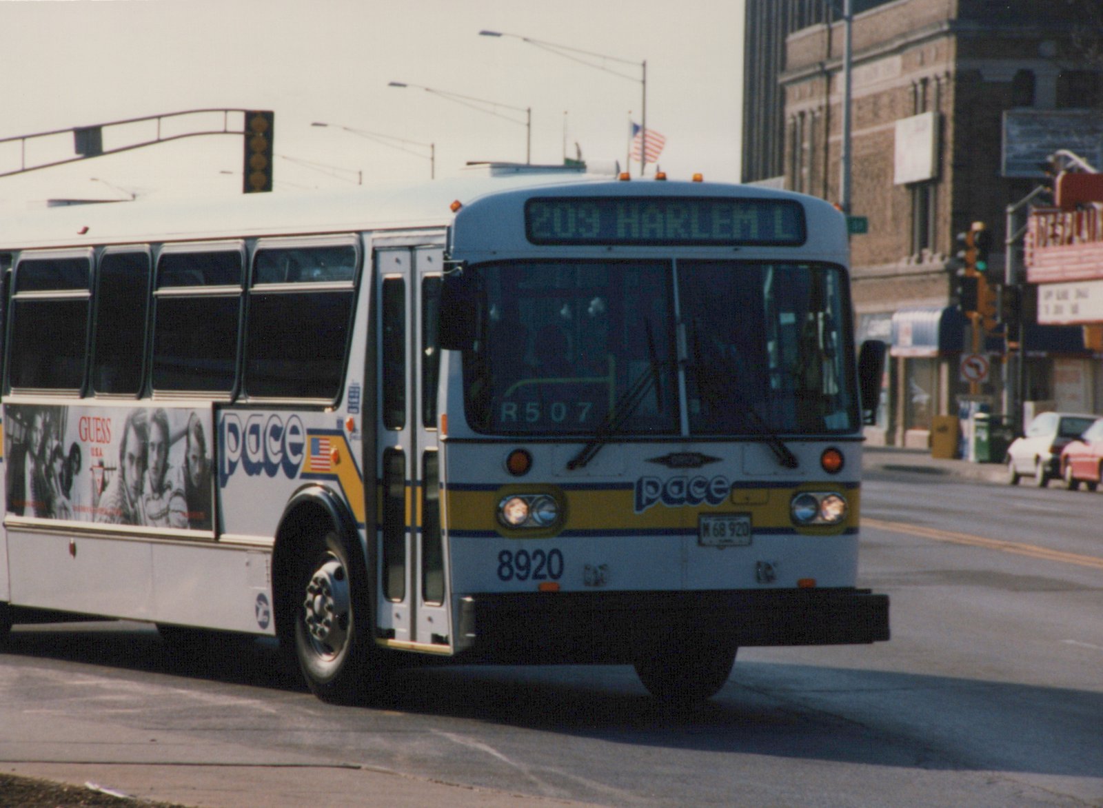 A white Pace motor bus with blue and yellow stripes, numbered 8920, is shown from a three-quarter front view on a city street, displaying route 209 Harlem on its front sign.
