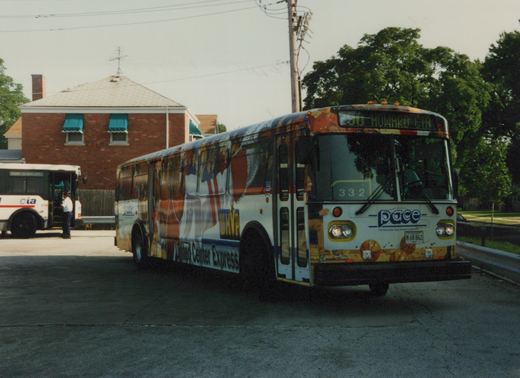 A white Pace bus with a colorful basketball-themed wrap is parked on a street, with a CTA bus visible in the background. The Pace bus displays the number 332 and route 330 Howard Ctr.