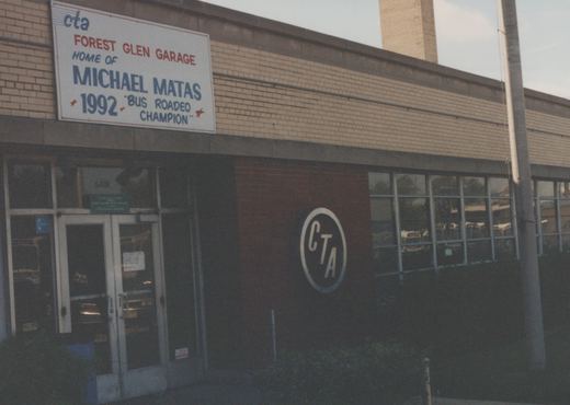 A brick building with a large sign reading 'CTA Forest Glen Garage, Home of Michael Matas, 1992 Bus Roadeo Champion', featuring the CTA logo and a view into the garage through large windows.