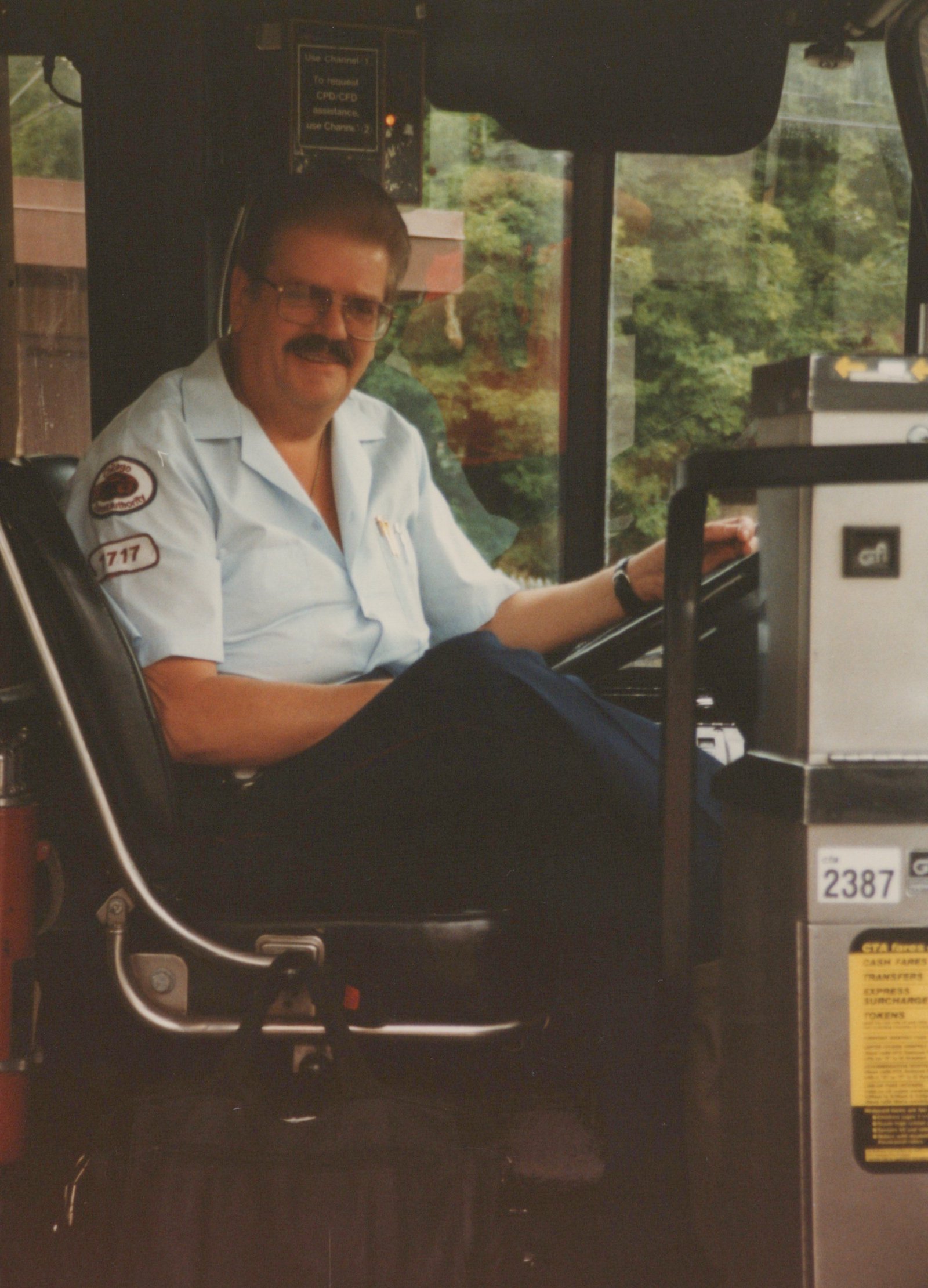 Interior view of a Chicago Transit Authority bus showing the driver in uniform seated at the wheel, with fleet number 2387 visible on the farebox.