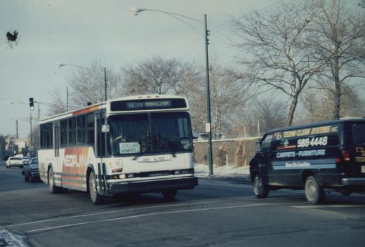 A white Neoplan bus on a city street with bare trees and snow, showing its destination as '22 TO HARRISON' and route as '22 CLARK HOWARD'.