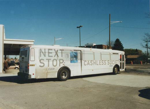 A white Pace bus with fleet number 8863 is parked on a paved lot, its side displaying a large American Express advertisement that reads 'NEXT STOP: CASHLESS SOCIETY'.