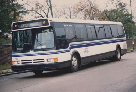 A white and blue Flxible Metro bus, fleet number 110, for METRO, is shown on a street with autumn trees in the background. The destination sign reads '22 to HOWARD'.