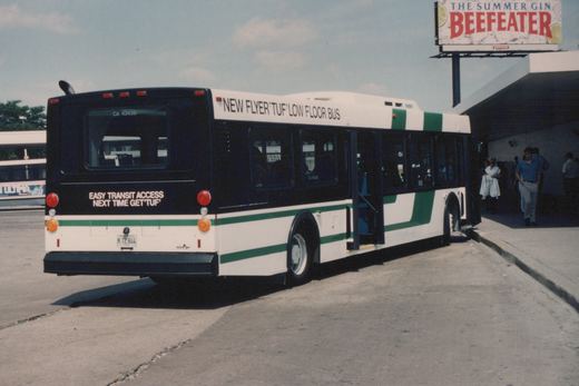 A white and green Chicago Transit Authority bus with the number CA 43438 is parked at a terminal, with people nearby and a Beefeater billboard in the background.