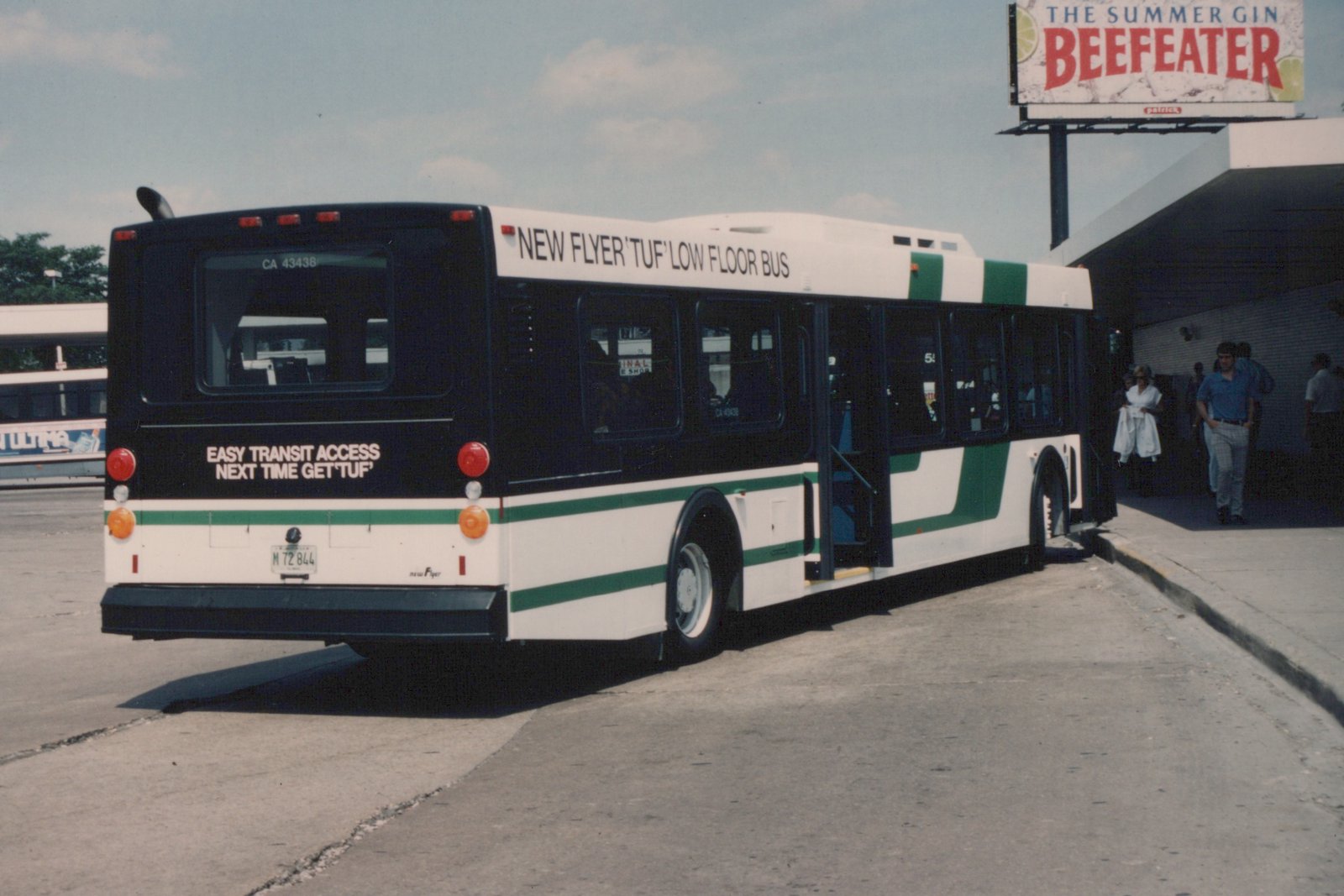 A white and green Chicago Transit Authority bus with the number CA 43438 is parked at a terminal, with people nearby and a Beefeater billboard in the background.