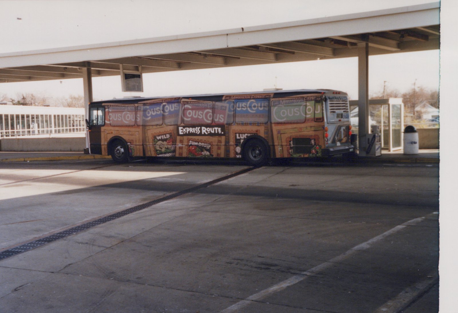 Side view of a Pace motor bus, number 209, with a colorful 'Marrakesh Express' advert, parked at a bus terminal on a clear winter day.